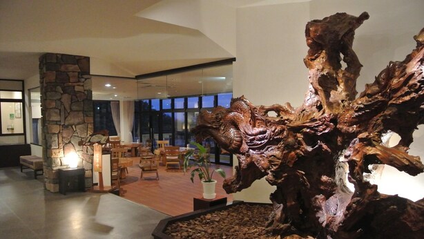 Una hall con una grande scultura in legno, un pilastro in pietra e una zona con posti a sedere.