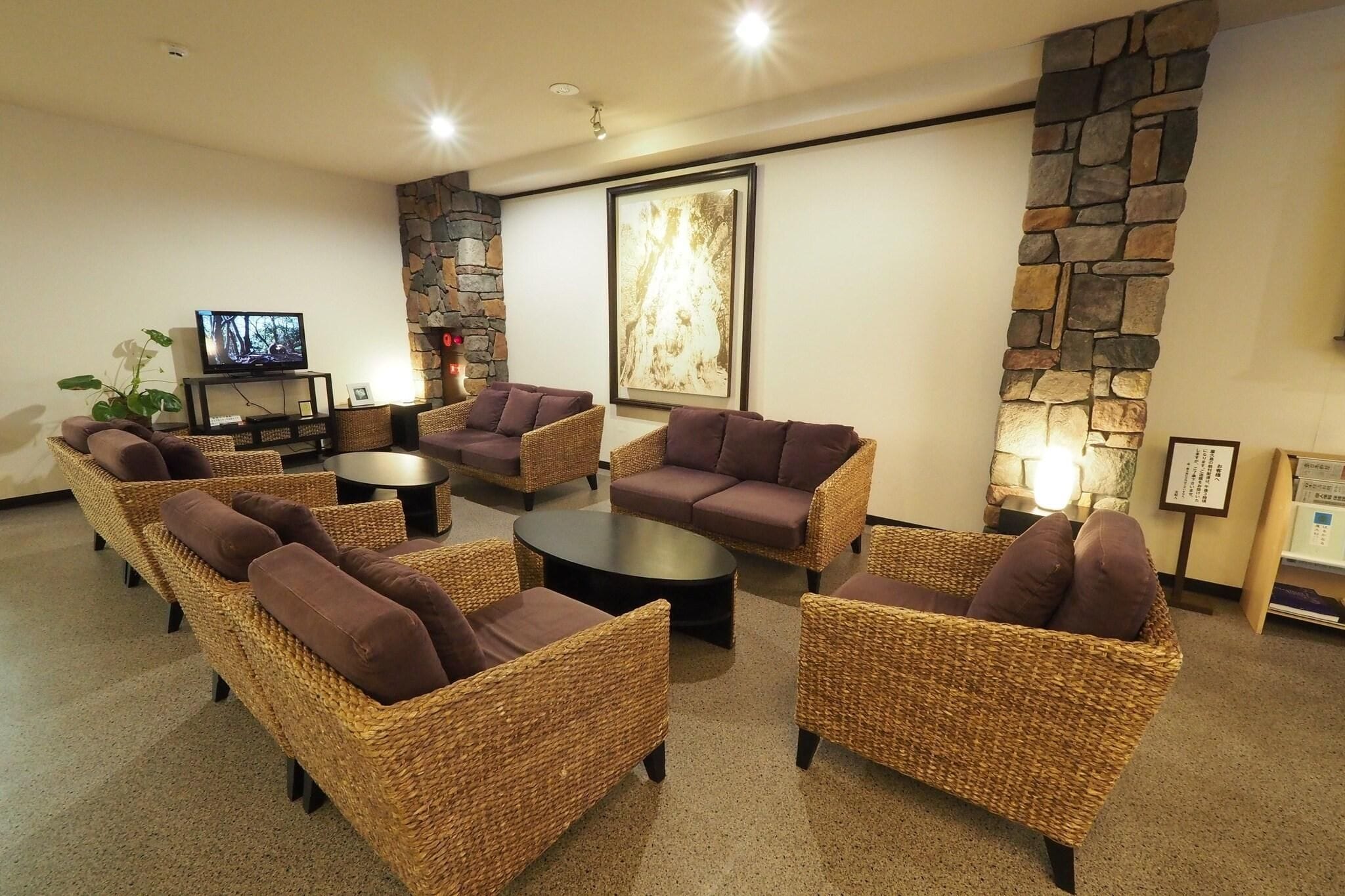 A lounge area with wicker furniture, a stone wall, and a television.