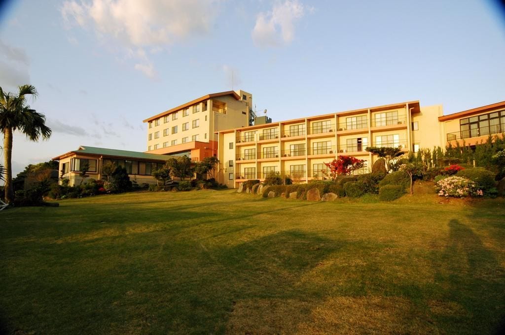 A multi-story hotel with a flat roof and a large lawn area in front.