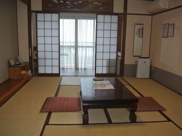 Une pièce de style japonais traditionnel, avec un sol recouvert de tatamis, une table basse et des portes coulissantes.
