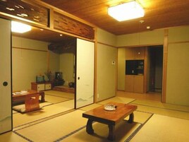 Una habitación japonesa tradicional con suelo de tatami, una mesa de madera baja y puertas correderas.