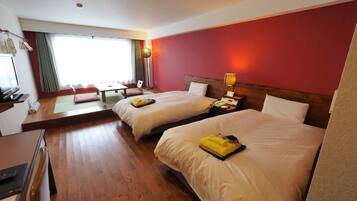 A hotel room with two beds, a desk, and a window with curtains.
