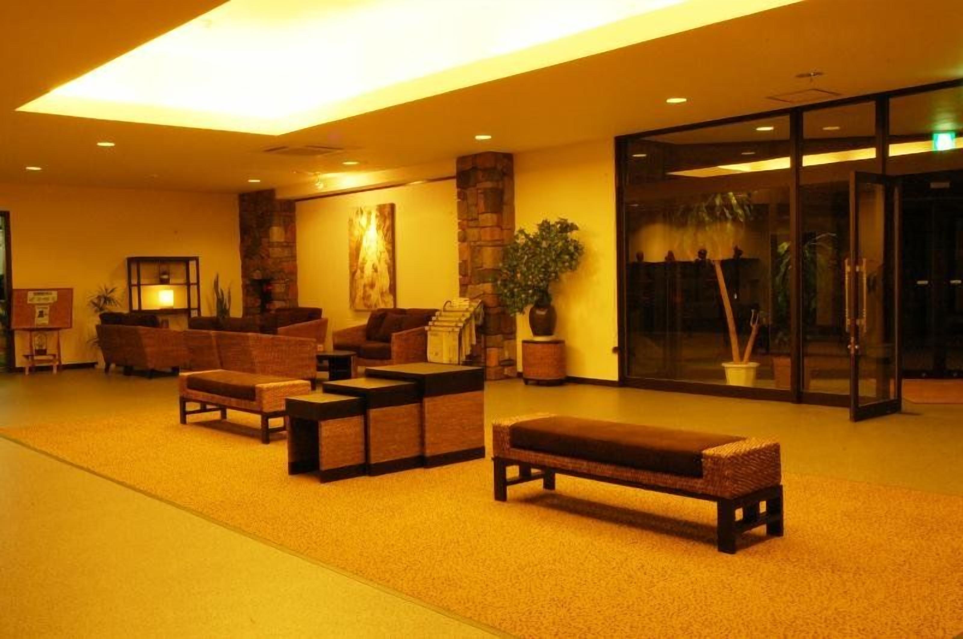 Un hall d’entrée avec des canapés, un banc, une cheminée et une porte vitrée donnant sur l’extérieur.
