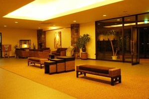 Un hall d’entrée avec des canapés, un banc, une cheminée et une porte vitrée donnant sur l’extérieur.