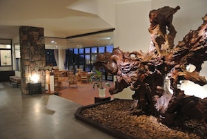 Un hall con una gran escultura de madera, un pilar de piedra y una zona de estar.