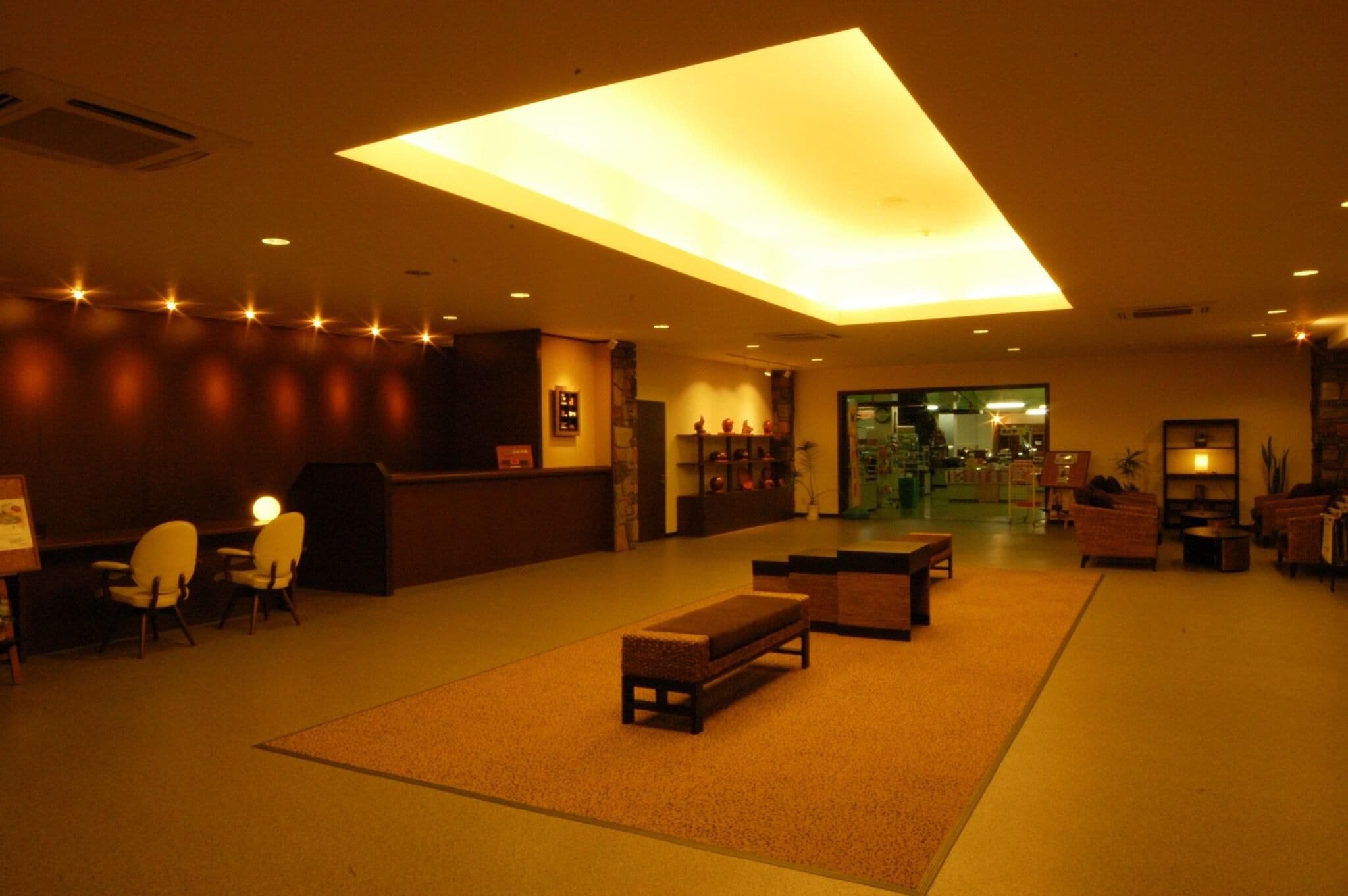 Una hall d'albergo con una reception, un'area salotto e un'ampia vetrata.