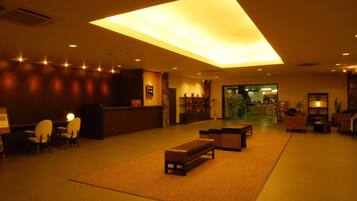Una hall d'albergo con una reception, un'area salotto e un'ampia vetrata.