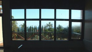 Una stanza con una grande finestra che si affaccia su un balcone e sul paesaggio esterno.
