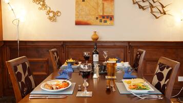 Una mesa de comedor dispuesta con platos de comida, copas de vino y una jarra de cerveza.