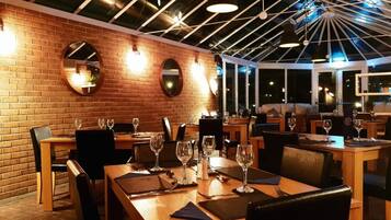 Un restaurant aux murs de briques, aux miroirs ronds et aux tables en bois, disposées pour le service.