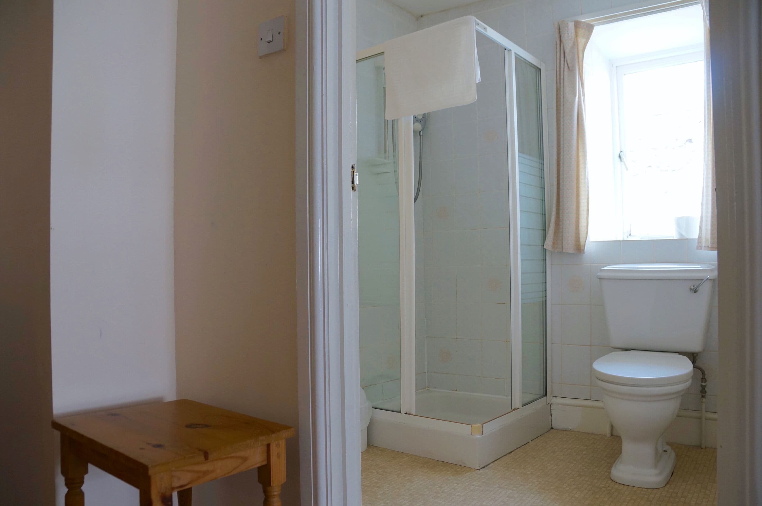 Un baño con inodoro, ducha y una pequeña mesa de madera.