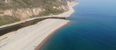 A coastal landscape with a sandy beach, a curved road, and a cliff.
