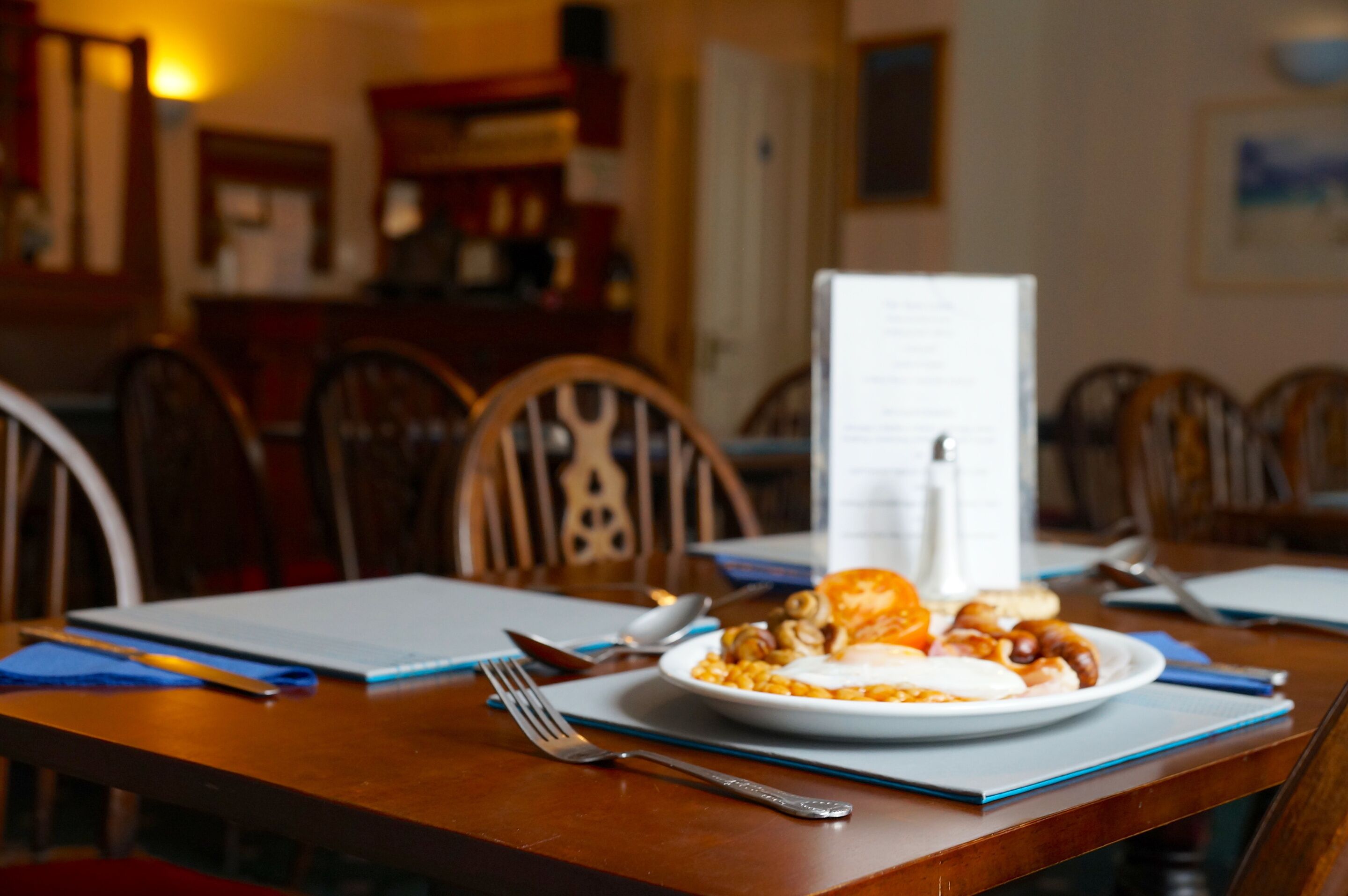 A dining table with a plate of food, a menu, and dining utensils.