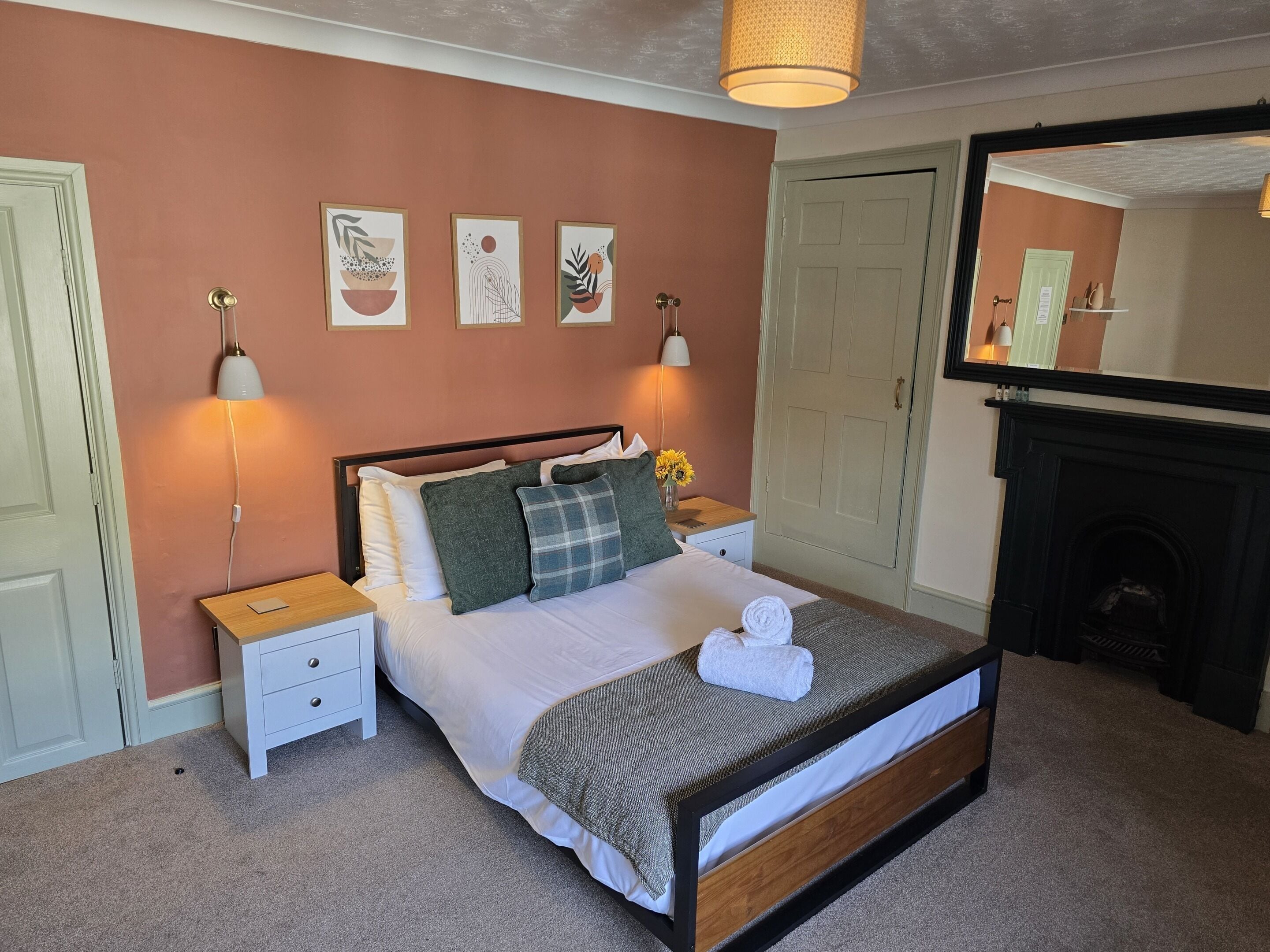 Une chambre à coucher bien aménagée, avec un lit, des lampes de chevet, une table de chevet, un miroir et une cheminée.