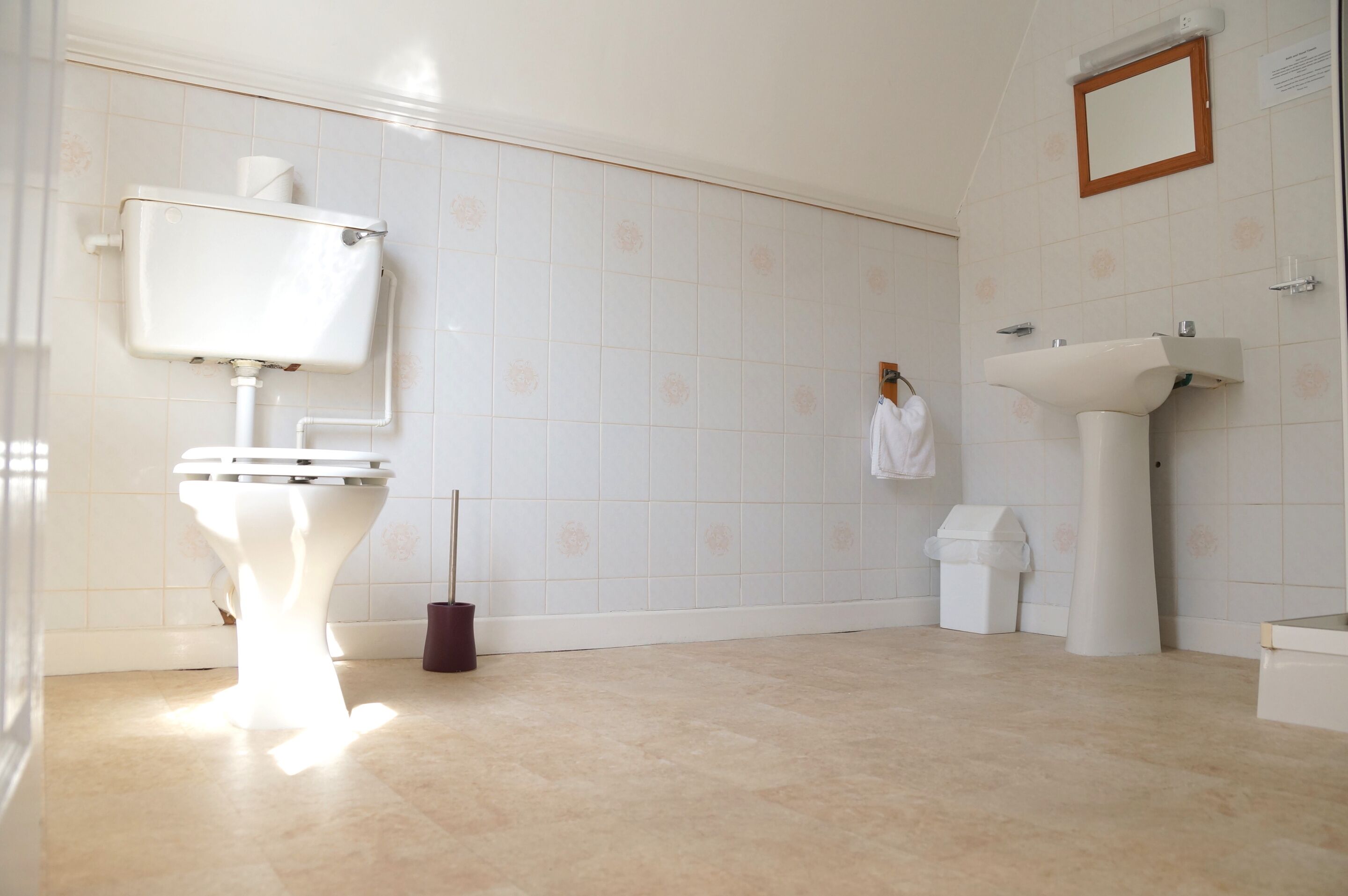 Et badeværelse med toilet, vask og spejl.