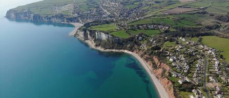 An aerial view of a coastal town with a beach, cliffs, and farmland.