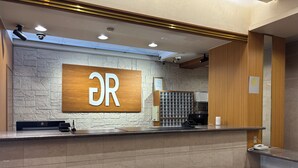 A reception desk with a stone wall backdrop, a wooden counter, and a bench. - Green Rich Hotel Aso Kumamoto Airport Artificial Hot Spring Futamata Yunohana (Kikuyo)