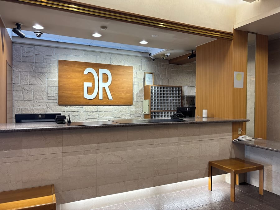 Un mostrador de recepción con un fondo de pared de piedra, una encimera de madera y un banco.