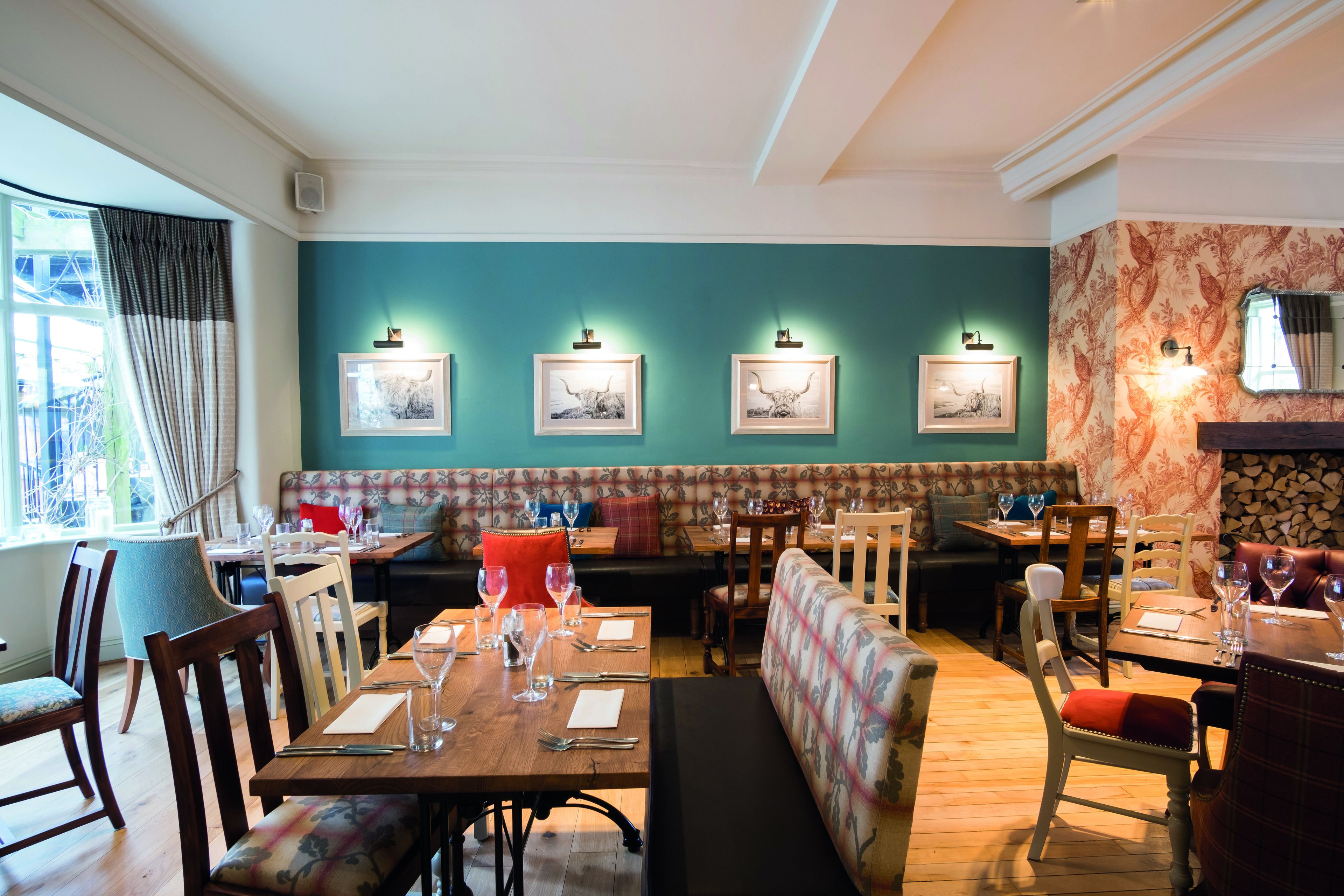 Un restaurante con mesas de madera, cabinas acolchadas y obras de arte enmarcadas en las paredes.