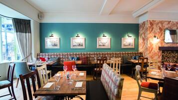 Un restaurante con mesas de madera, cabinas acolchadas y obras de arte enmarcadas en las paredes.