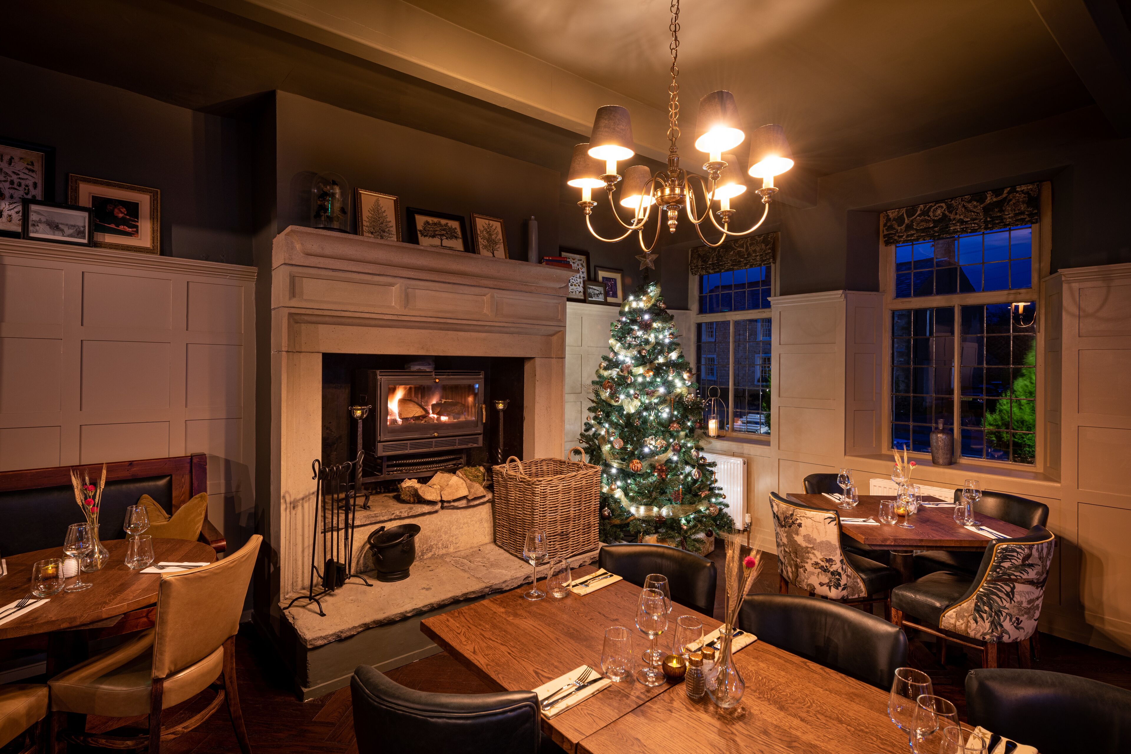 Un rincón comedor acogedor con chimenea, árbol de Navidad y candelabro.