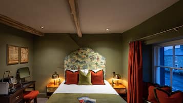 A bedroom with a bed, two bedside tables, a desk, a chair, and a window with curtains.