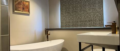 Une salle de bain avec une baignoire sur pieds, un lavabo et une fenêtre décorée.
