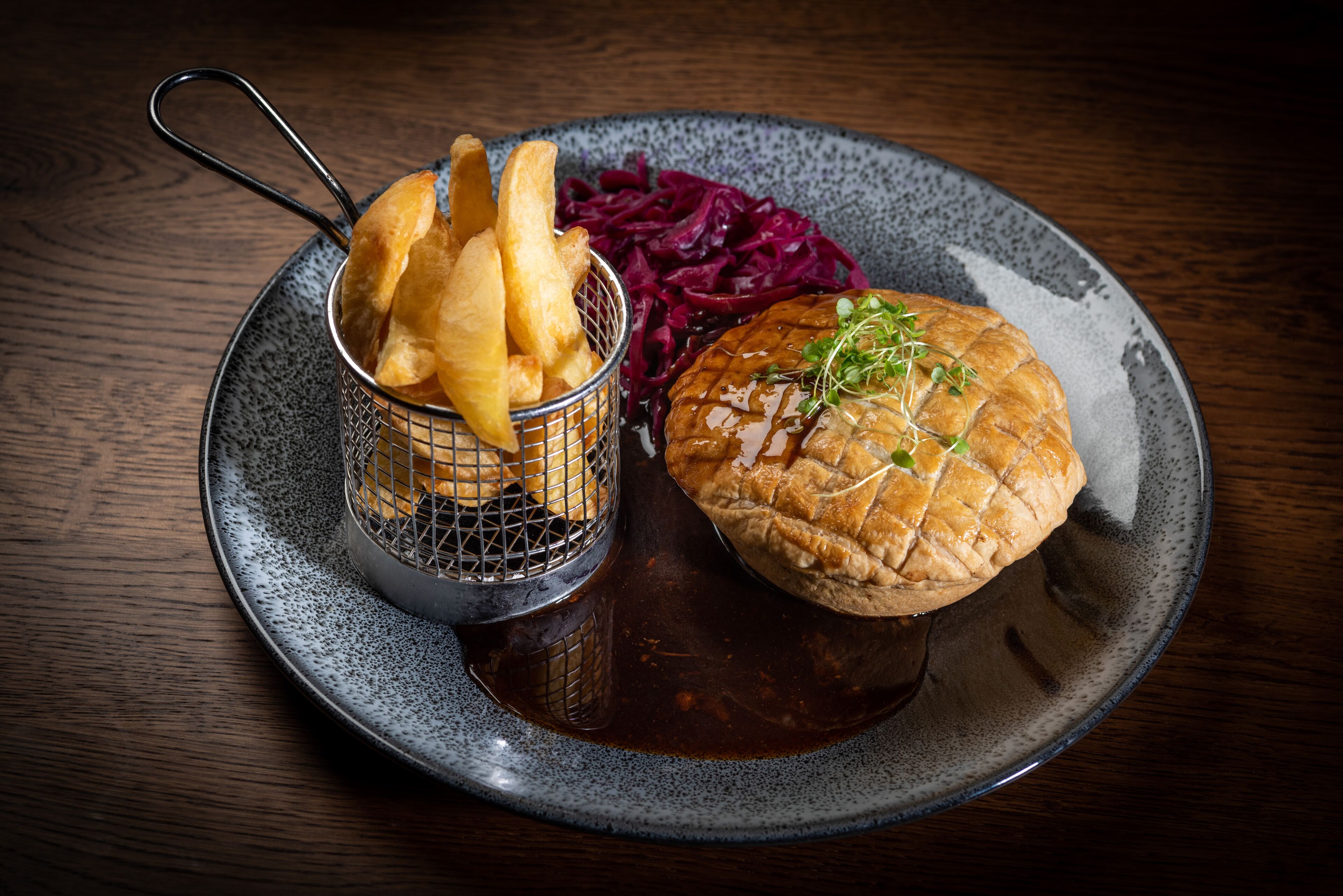 A plate with a burger, fries, and red cabbage.