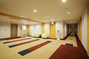 Un pasillo de hotel con piso alfombrado, zona de estar y mostrador de recepción.