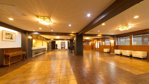 A spacious lobby with a wooden floor, a reception desk, and seating areas. - Highness Hotel Kurume (Kurume)