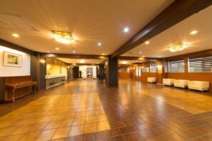 Un vestíbulo amplio con suelo de madera, mostrador de recepción y zonas de estar.