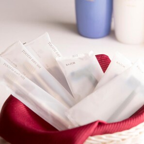 A basket containing several white packages with 'TOOTHBRUSH' and 'RAZOR' printed on them. - Highness Hotel Kurume (Kurume)