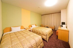 Habitación de hotel con dos camas, un escritorio, una silla, una mesita y una cortina.