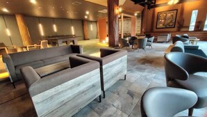 A modern lobby with a grey sofa, black chairs, and a wooden accent wall. - Arden Hotel Aso (Minamiaso)
