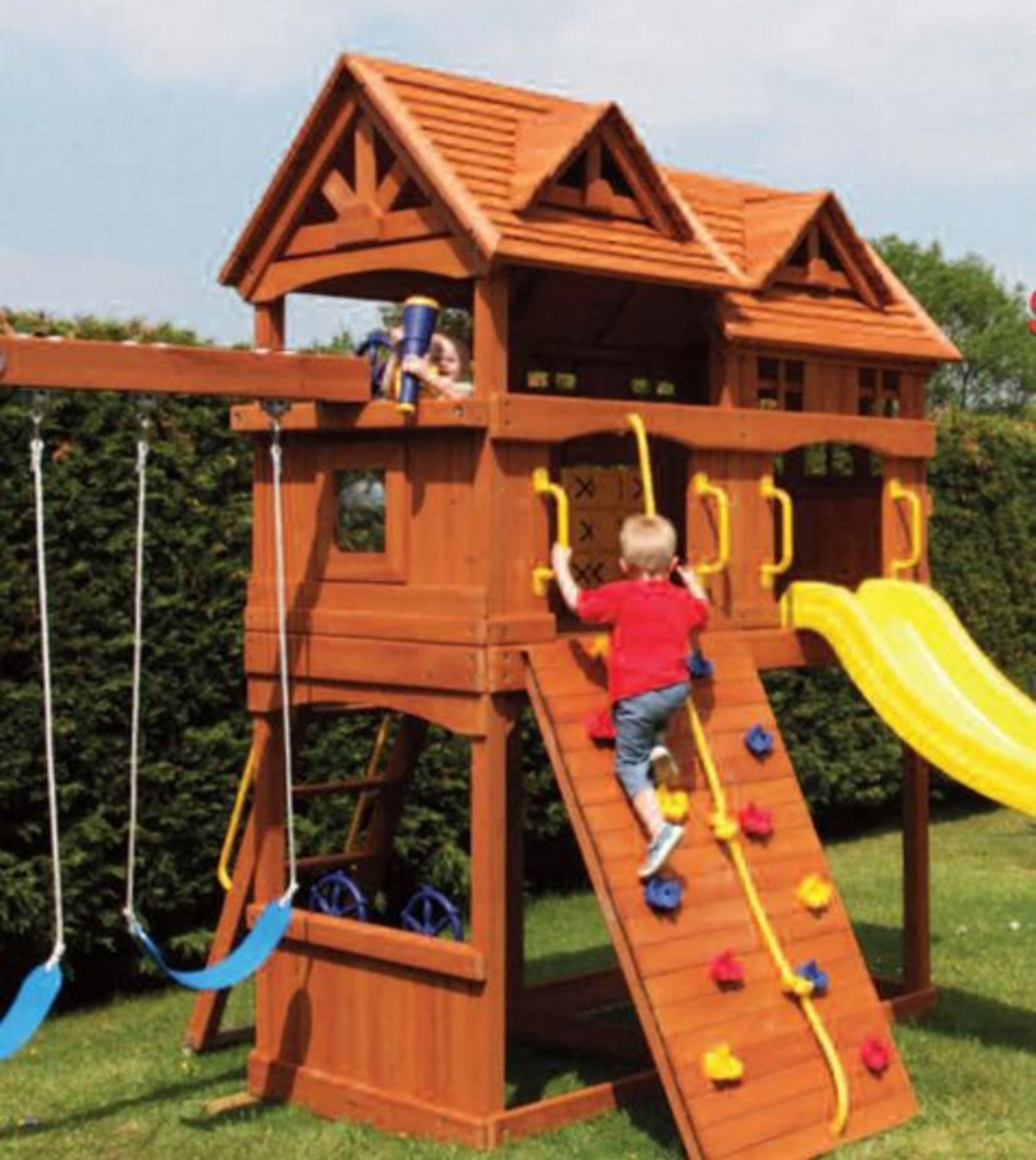A wooden play structure with a slide, climbing wall, and rope ladder.