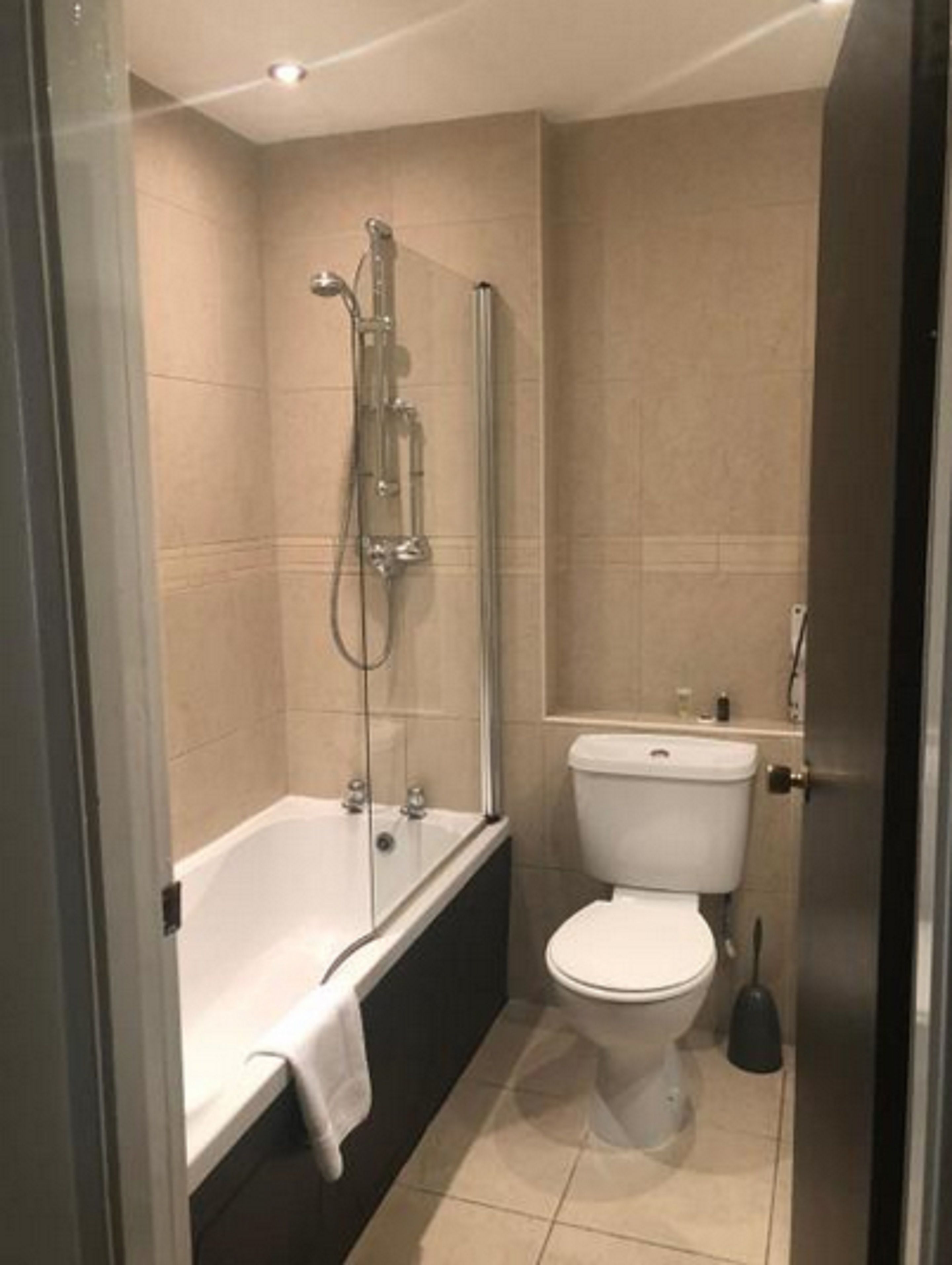 Moderni kylpyhuone, jossa on lasiseinällä varustettu suihku, erillinen kylpyamme ja wc.