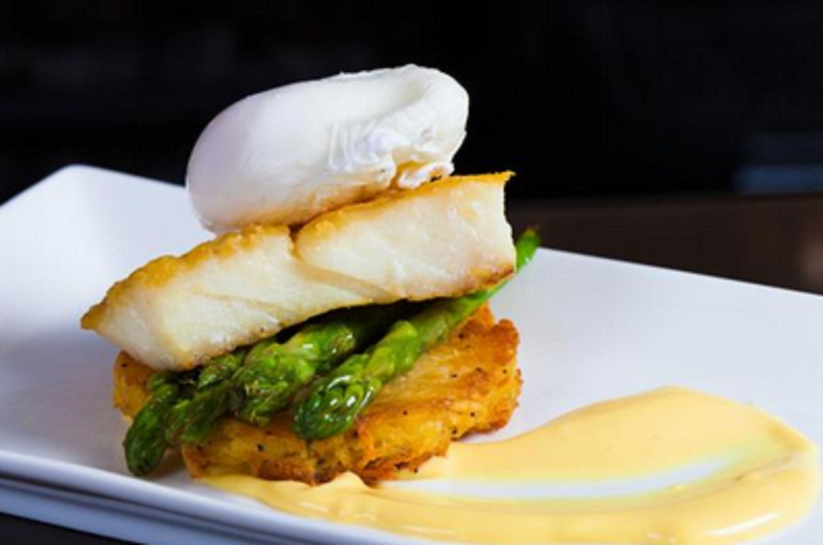 A dish with a poached egg, asparagus, and a creamy sauce on a white plate.