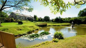 A serene pond with lily pads, a wooden bench, and a building in the background. - The Sitwell Arms Hotel (Sheffield)