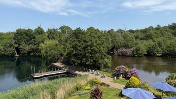 A lakeside view with a dock, lounge chairs, and umbrellas.