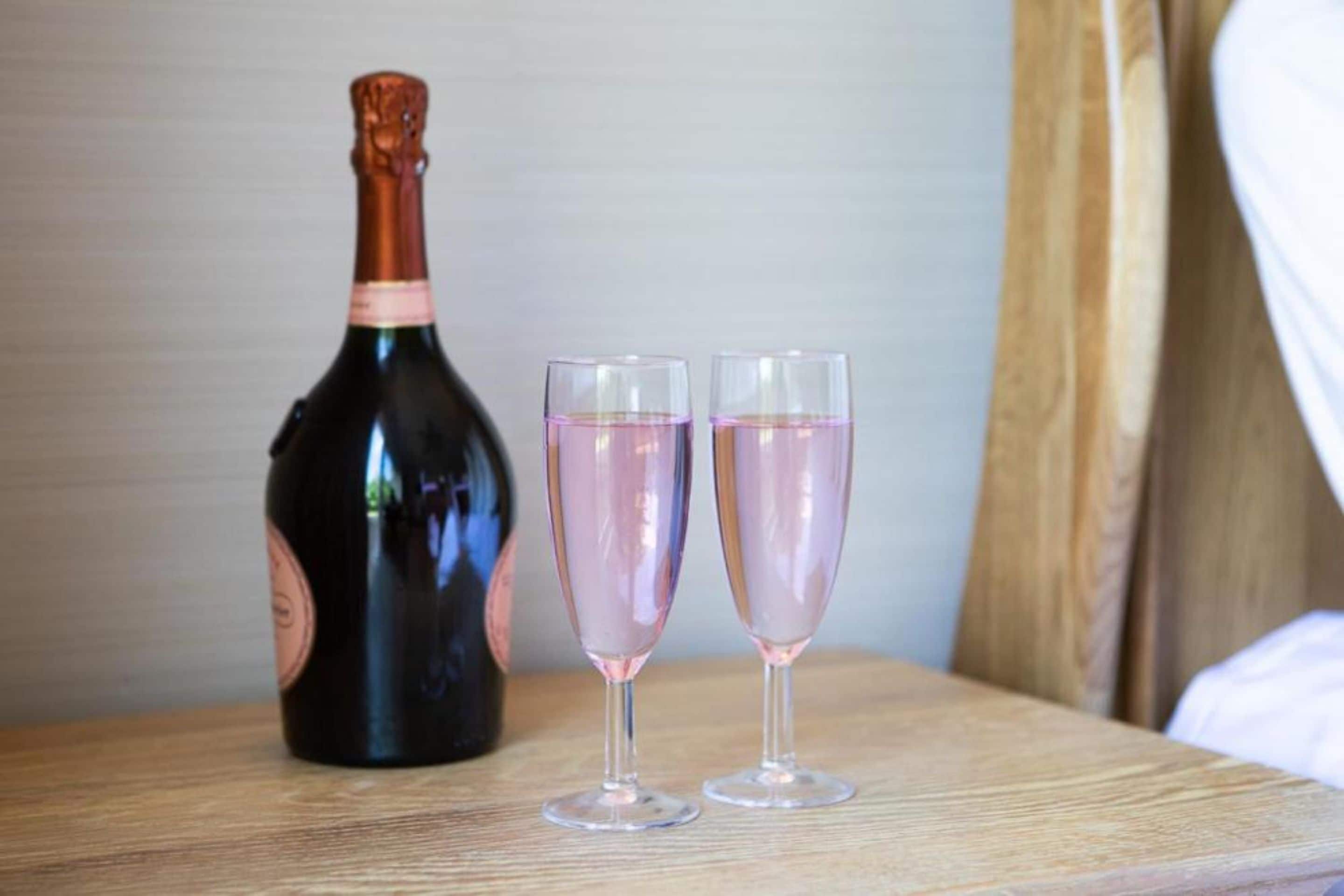 A bottle of champagne and two glasses on a wooden surface.