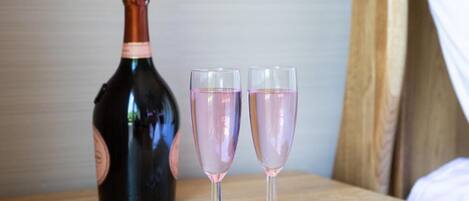 A bottle of champagne and two glasses on a wooden surface.