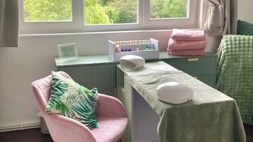 A room with a chair, a table, a radiator, and a window with curtains.