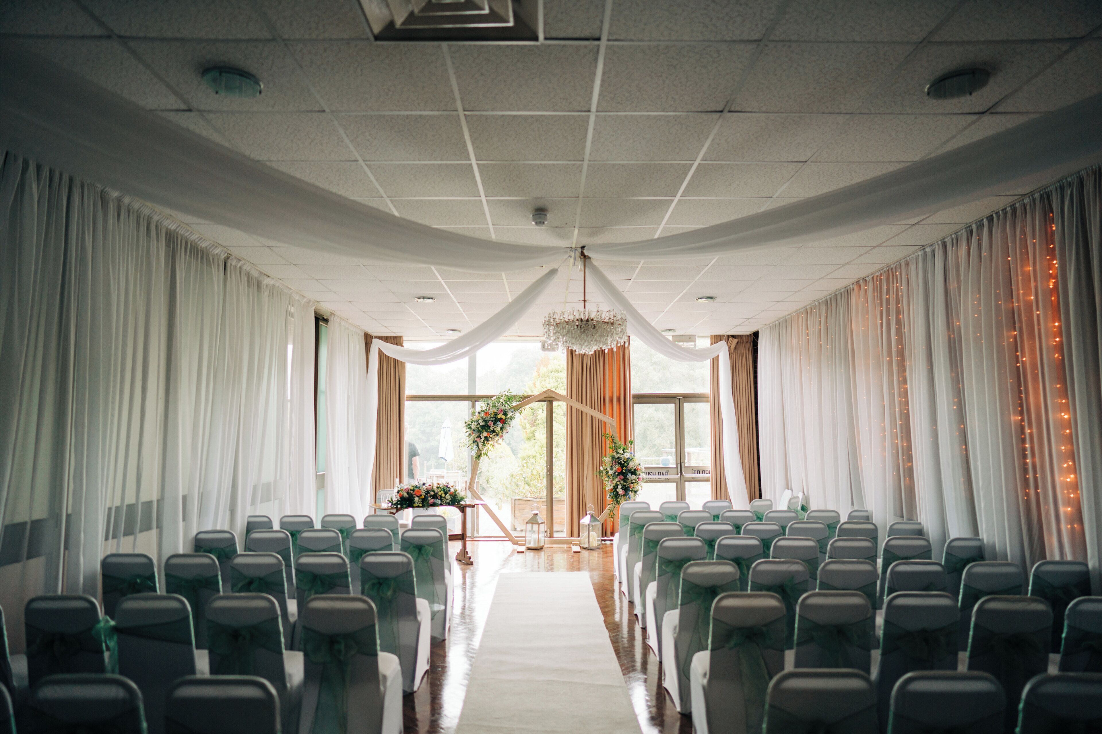 A venue with rows of chairs, a central aisle, and draped curtains.