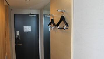 A hallway with a black door, a coat rack with black hangers, and a sign on the door.