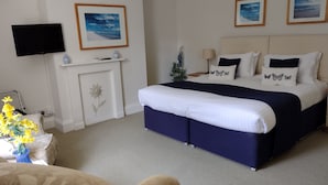 Habitación de hotel con una cama grande, televisión de pantalla plana en la pared y chimenea.