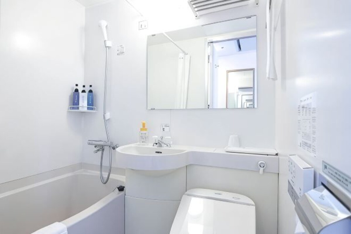 A bathroom with a bathtub, sink, toilet, and a mirror.
