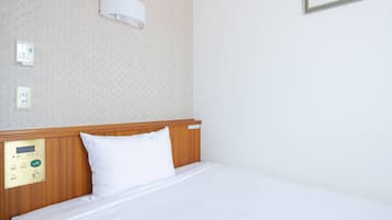 A hotel room with a wooden headboard, a control panel, a white pillow, and a framed picture on the wall.