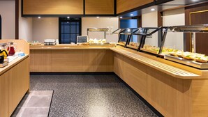 Una cocina moderna con armarios de madera, encimera de acero inoxidable y una zona de bufé con diferentes alimentos.