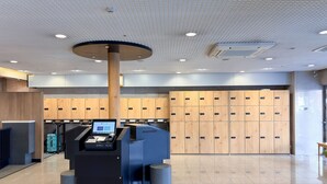 Un área de recepción moderna con quiosco informático, espacio para guardar equipaje y una fila de taquillas.