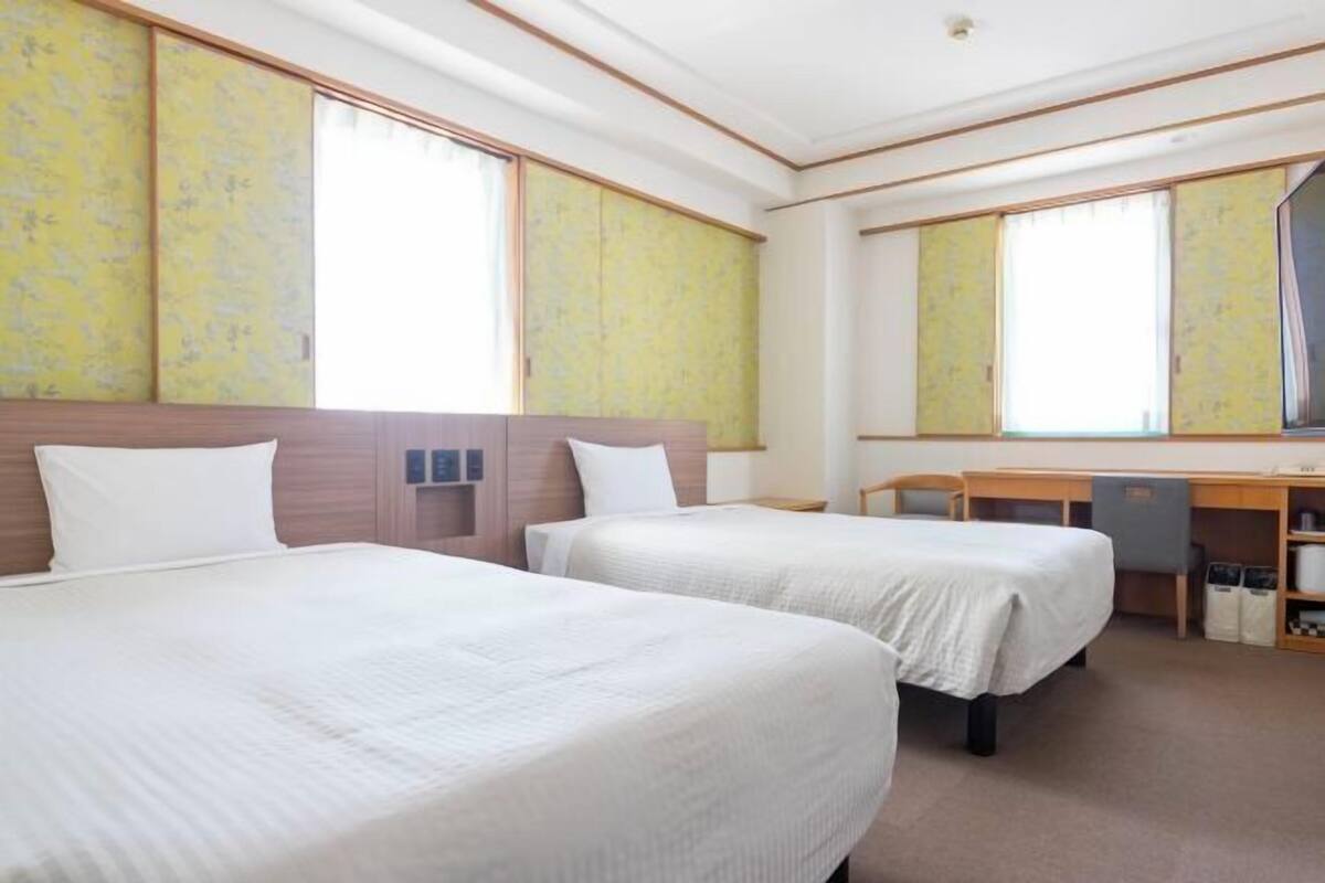 Een hotelkamer met twee bedden, een bureau en een spiegel.
